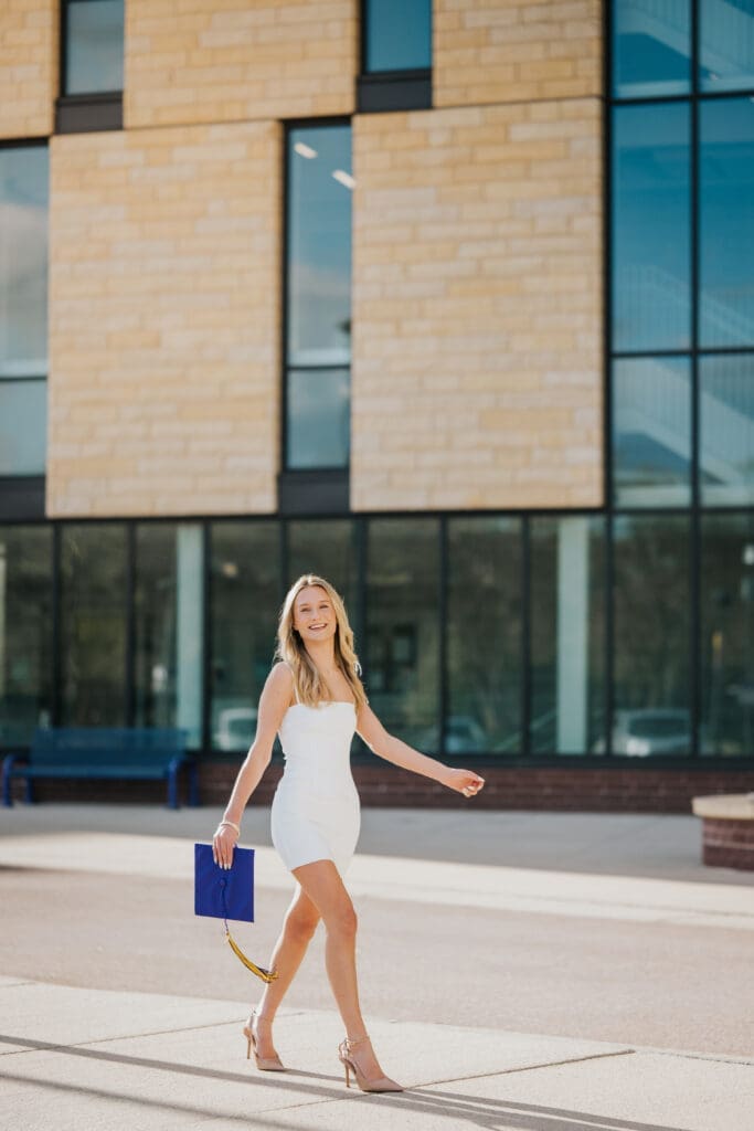 College graduate walking on campus at Minnesota State University Mankato during golden hour
