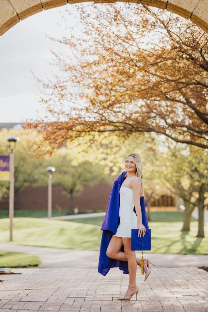 College graduate walking under campus archway at Minnesota State University Mankato