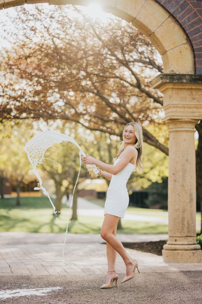 College graduate posing under archway at Minnesota State University Mankato during golden hour