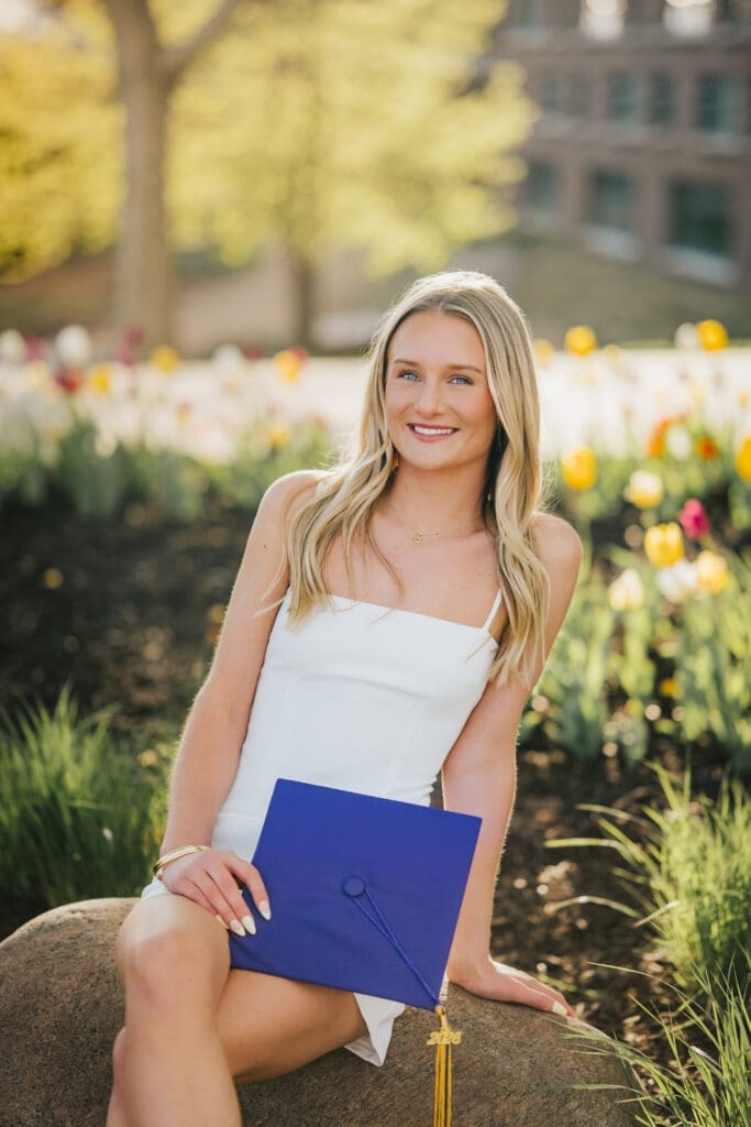 College graduate sitting with graduation cap during spring grad session at Minnesota State University Mankato