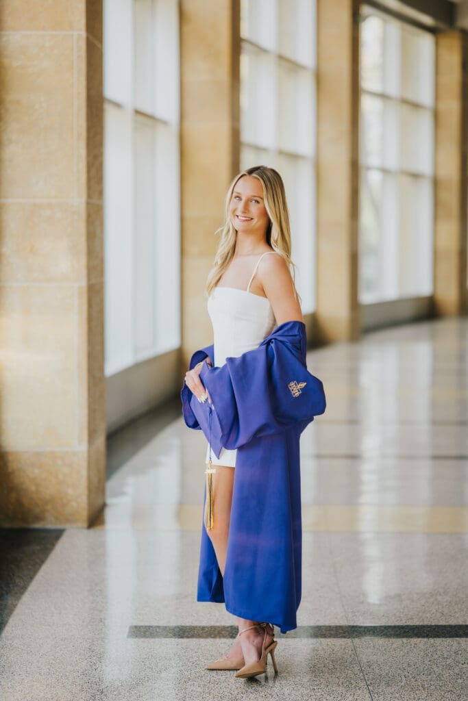 College graduate in blue cap and gown inside Minnesota State University Mankato campus building
