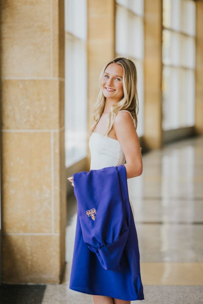 College graduate holding purple cap and gown inside Minnesota State University Mankato