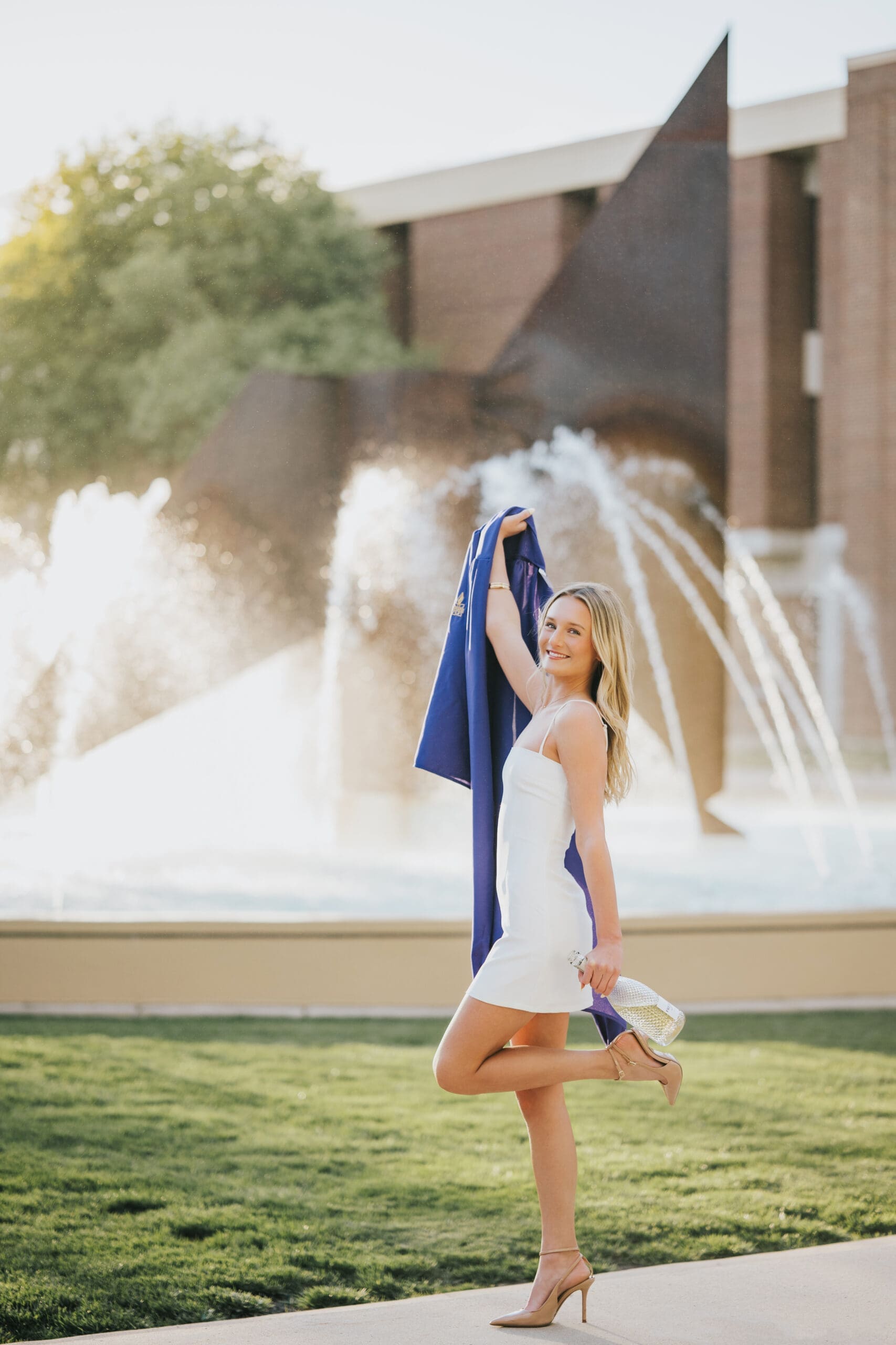 College graduate posing by fountain during golden hour at Minnesota State University in Mankato MN