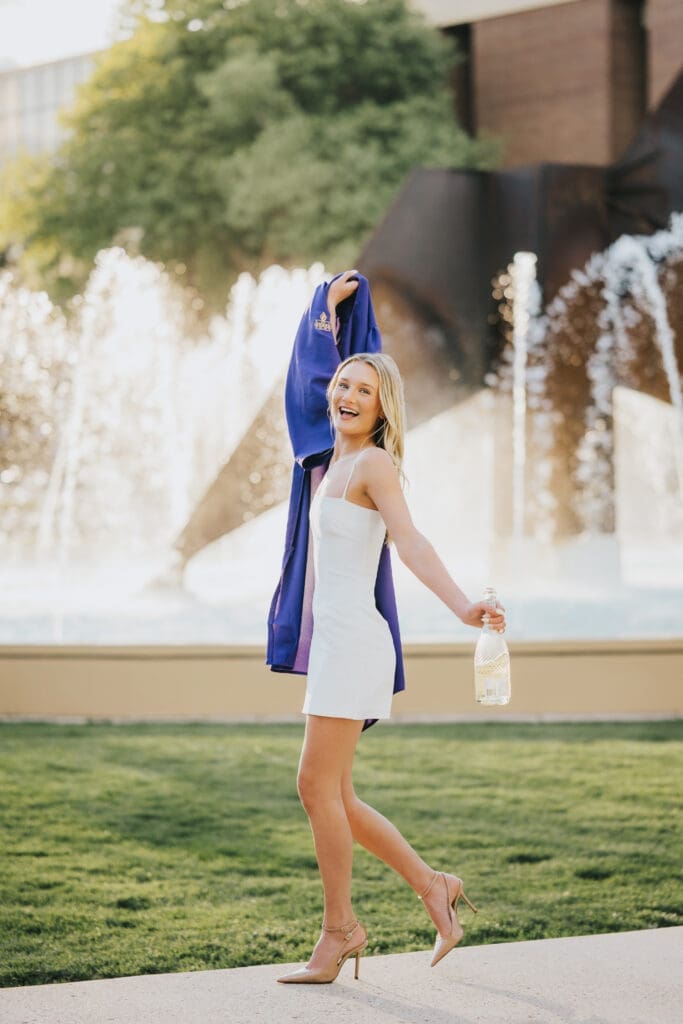 College graduate walking by fountain during golden hour at Minnesota State University Mankato
